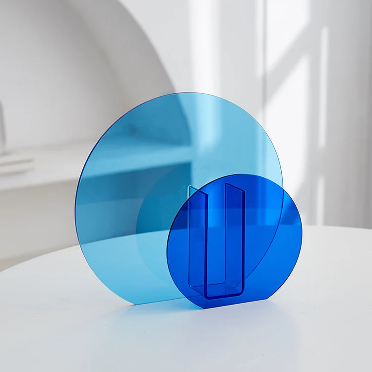 Vase Acrylique Bleu Cobalt et Bleu Ciel Rond | Design Rétro Géométrique Pavao Studio Vase acrylique design bleu cobalt, de forme ronde, avec un panneau circulaire bleu transparent pour un effet color-block moderne. Posé sur une table blanche.