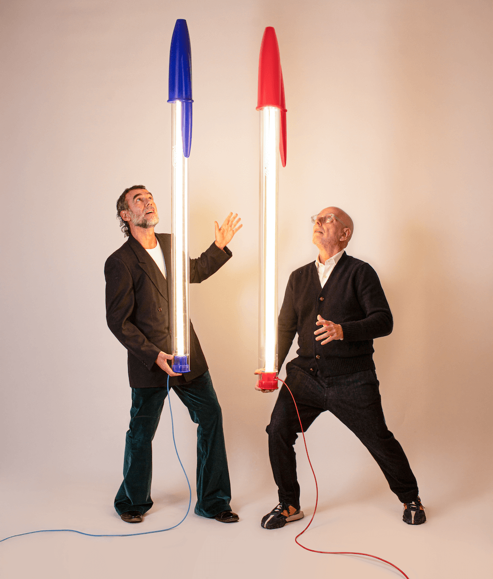 Lampe BIC – Seletti x BIC | Design Mario Paroli Stefano Seletti et Mario Paroli, créateur de la lampe Bic Seletti, jouant avec deux lampes géantes design rouge et bleue