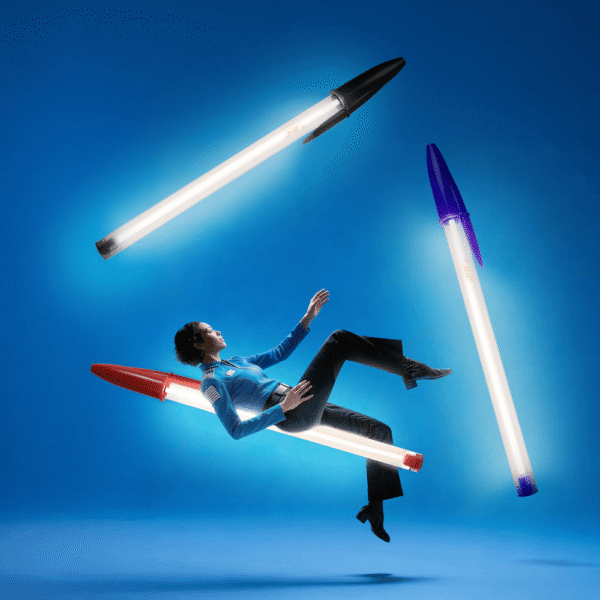 Lampe Bic Seletti géante rouge, noire et bleue en suspension avec modèle flottant sur fond bleu