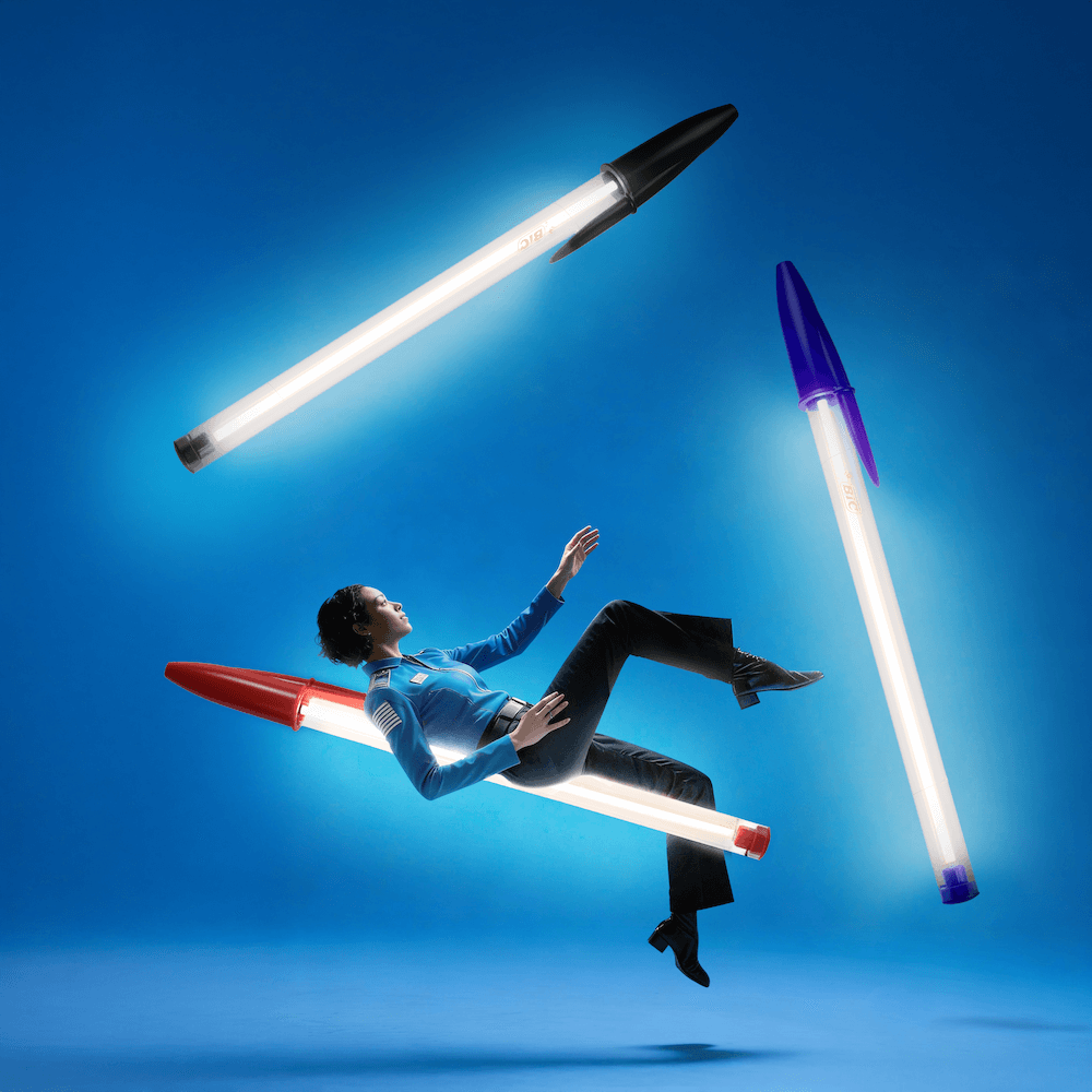Lampe Bic Seletti géante rouge, noire et bleue en suspension avec modèle flottant sur fond bleu