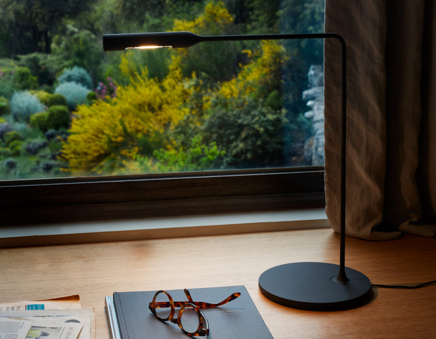 Lampe de bureau Flo Desk Lumina noir soft-touch en situation devant une fenêtre