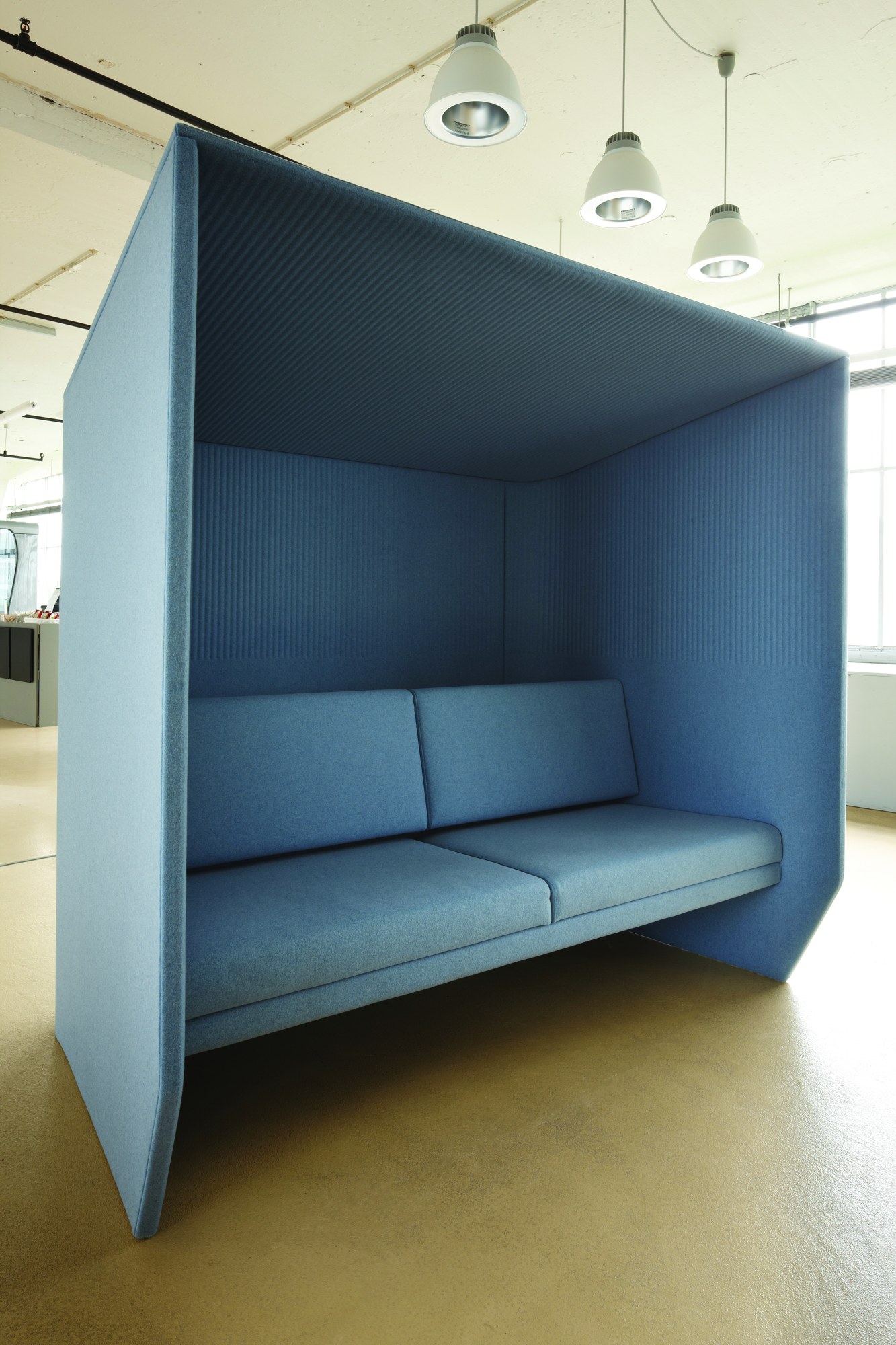 Alcôve acoustique BuzziHub par BuzziSpace, simple ou double alcôve acoustique BuzziHub BuzziSpace bleue avec banquette dans un espace de bureau