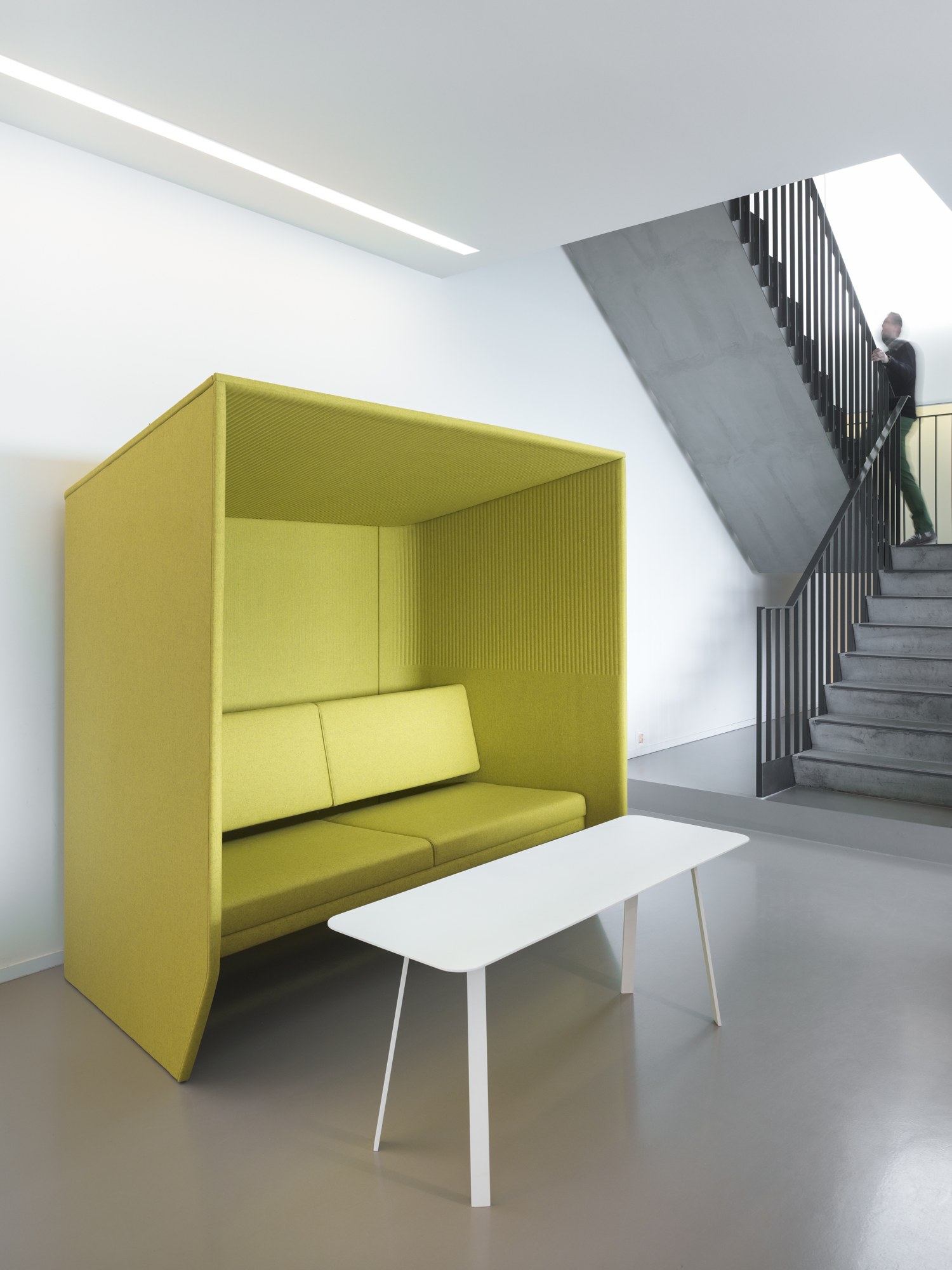 Alcôve acoustique BuzziHub par BuzziSpace, simple ou double alcôve acoustique BuzziHub BuzziSpace vert anis avec table basse près d'un escalier