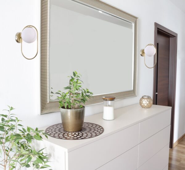 applique anneau ovale globe opale laiton au dessus d une commode pres d un grand miroir