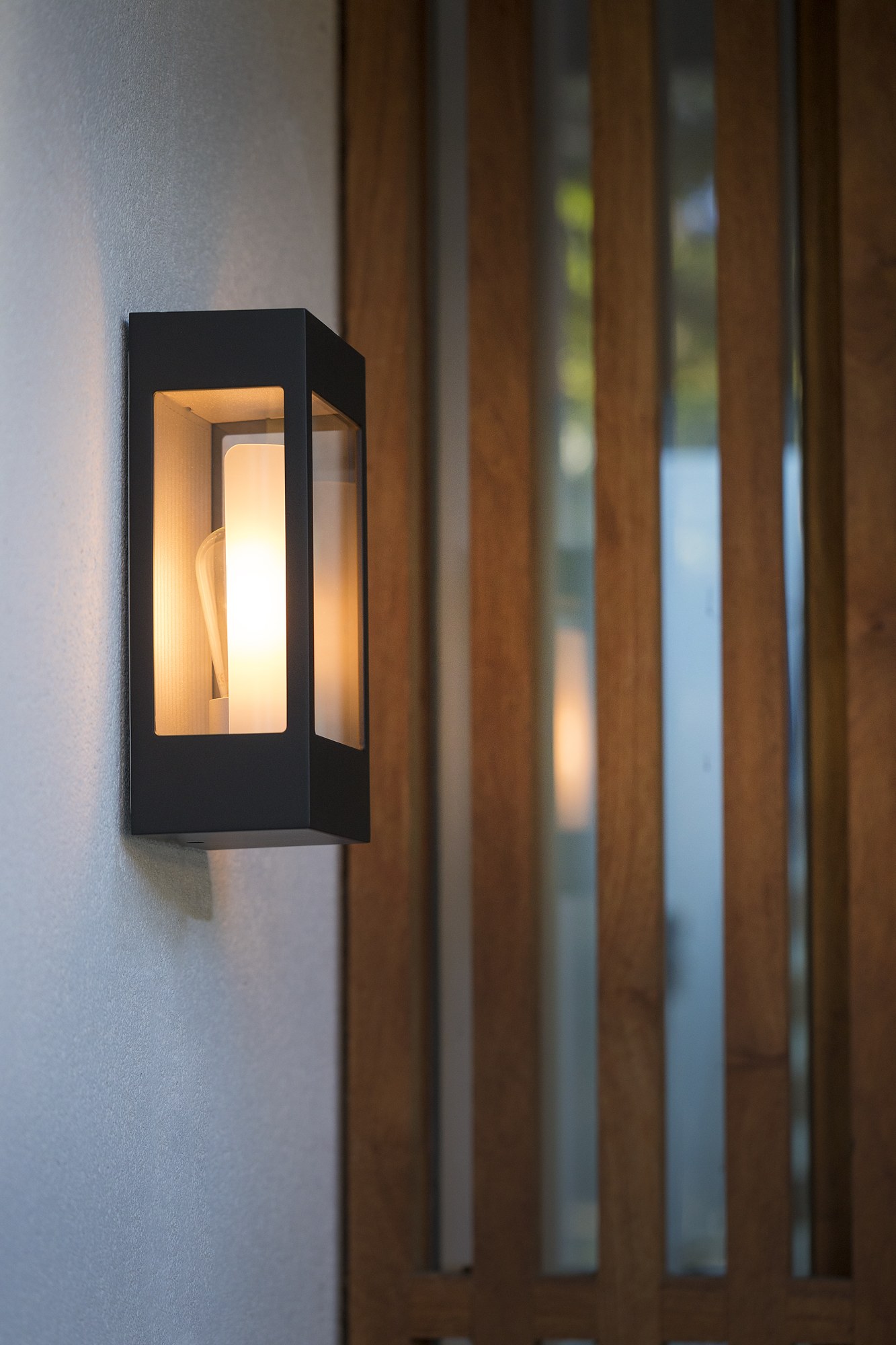 Applique Brick² en aluminium, verre ou PMMA, Roger Pradier applique Brick² noir velours allumée sur un mur enduit près d un claustra en bois