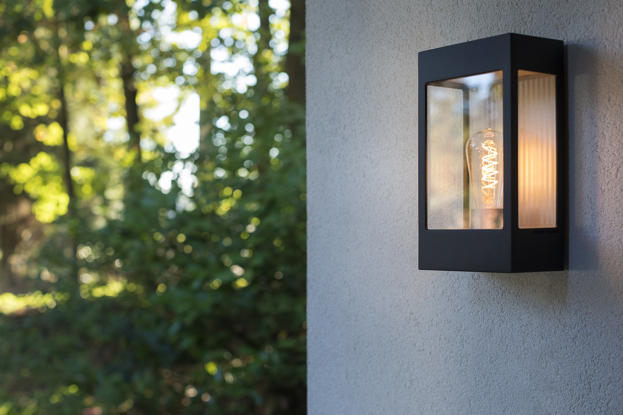 Applique Brick² en aluminium, verre ou PMMA, Roger Pradier applique Brick² noir velours avec ampoule à filament devant un feuillage