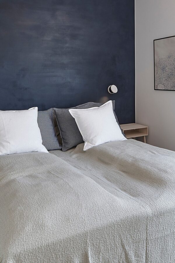 applique Dot Wall W120 Antidark blanche au-dessus d'une tête de lit dans une chambre