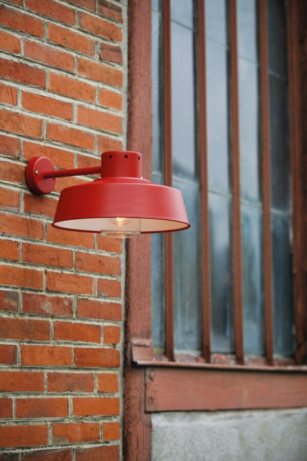 applique Faktory rouge tomate en aluminium fixée sur un mur de brique
