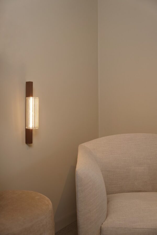 Applique Lirra LED 40 cm allumée près d'un fauteuil, finition Dark Coffee