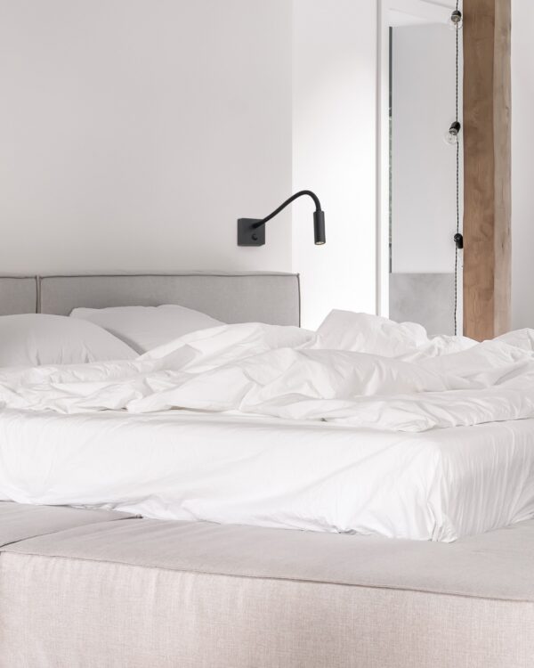 applique liseuse Flex Wall Antidark noire au-dessus d'une tête de lit, vue rapprochée
