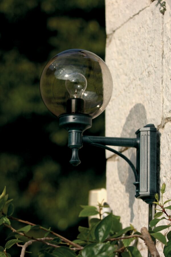 applique Moon globe 200 mm N° 1 montante teinte patine vert de gris avec globe fumé sur un mur de pierre claire