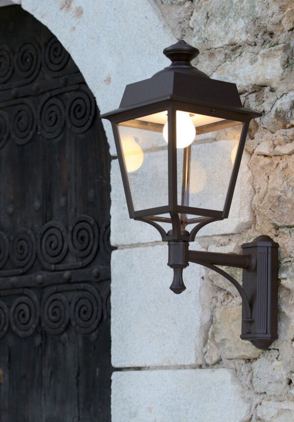 applique Place des Vosges Évolution montante à console rouille devant une porte ancienne en bois et pierre blonde