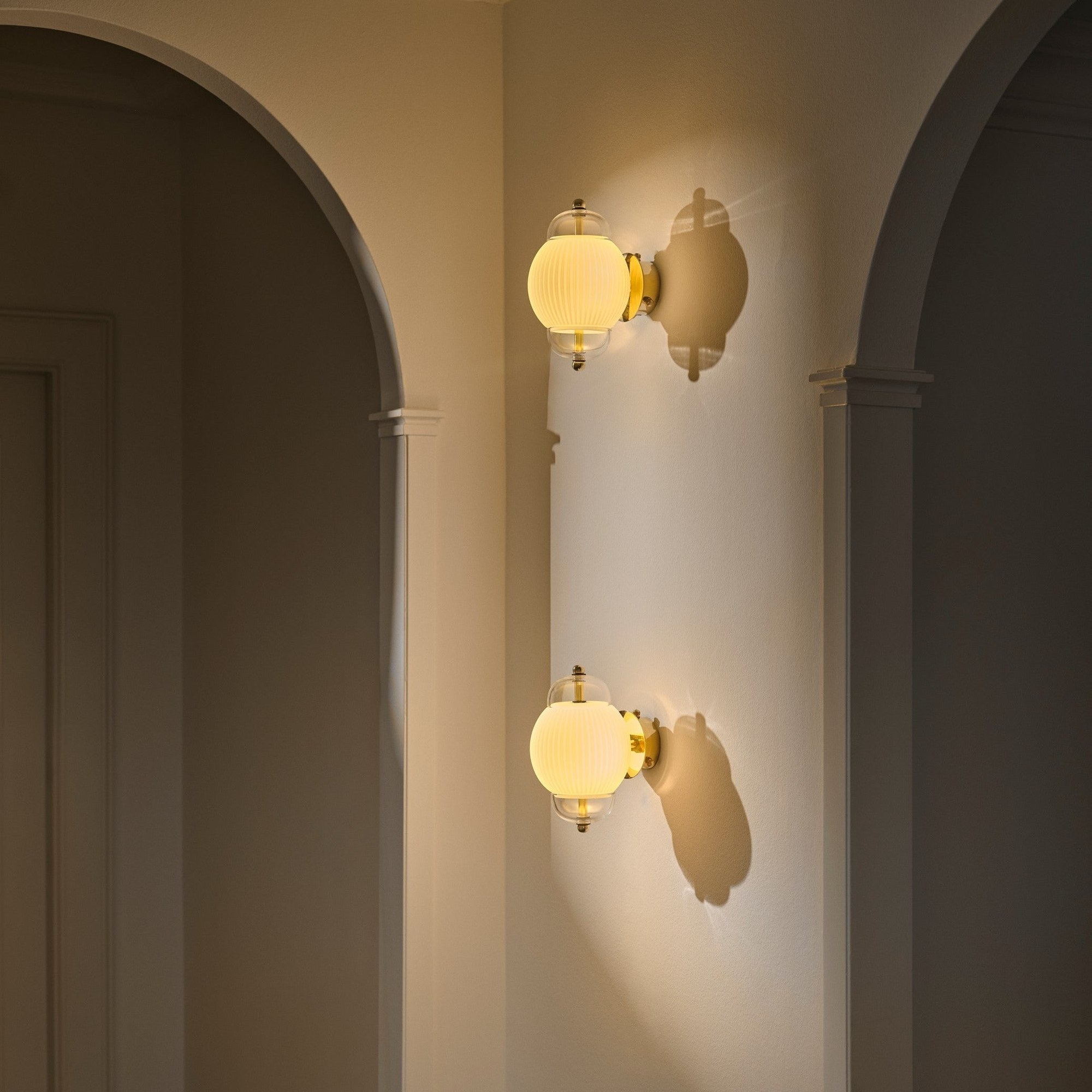 Applique murale Shahin en verre soufflé et laiton par Design by Us applique Shahin Design by Us, deux appliques superposées dans un couloir à arches