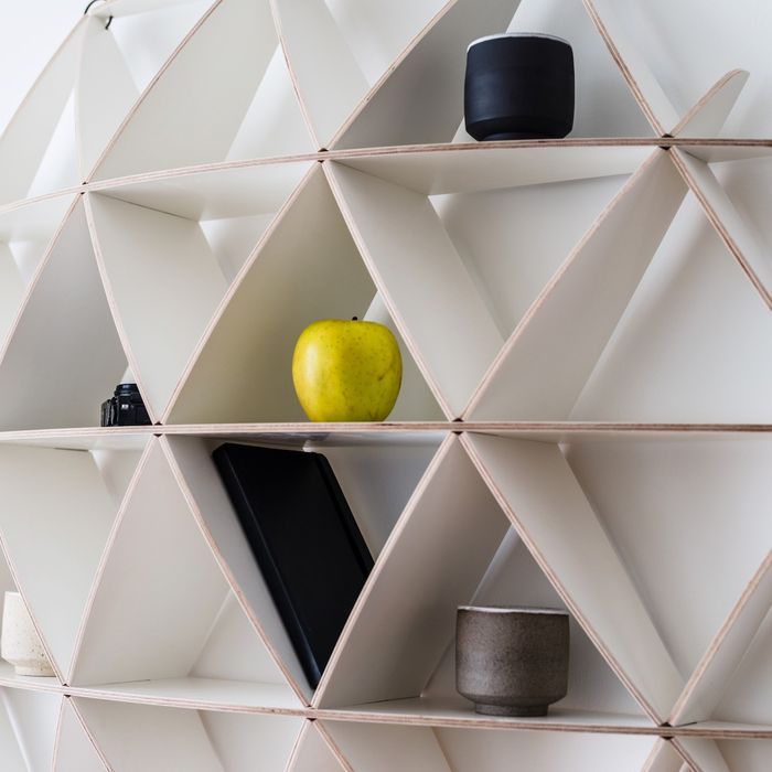 Bibliothèque ouverte : laquelle choisir pour votre mur ? Bibliothèque ouverte Comb de Jaanus Orgusaar, alvéoles triangulaires en bouleau avec une pomme et un vase