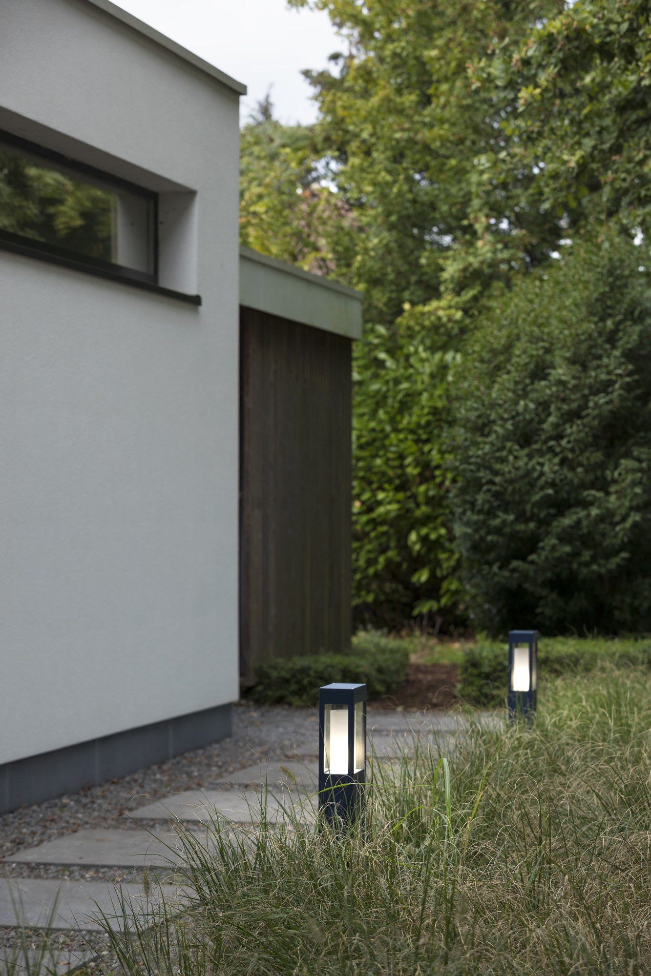 Borne Brick² en aluminium, 3 hauteurs, prises en option, Roger Pradier borne Brick² bleu acier allumée dans une allée de jardin devant une maison contemporaine