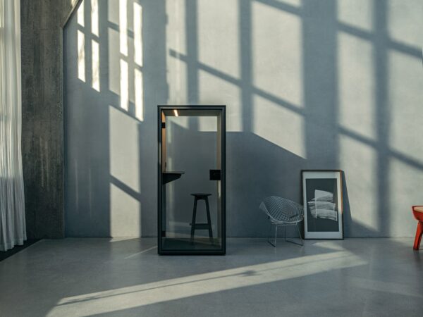 Phone Box ou Cabine Insonorisée : Laquelle Choisir pour son Open Space ? Cabine téléphonique bureau FOCUS Berlin Acoustics, cabine noire installée dans un loft, avec tabouret