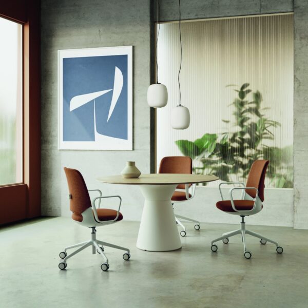 chaise de bureau Inclass Orus autour de la table ronde dans un bureau en béton