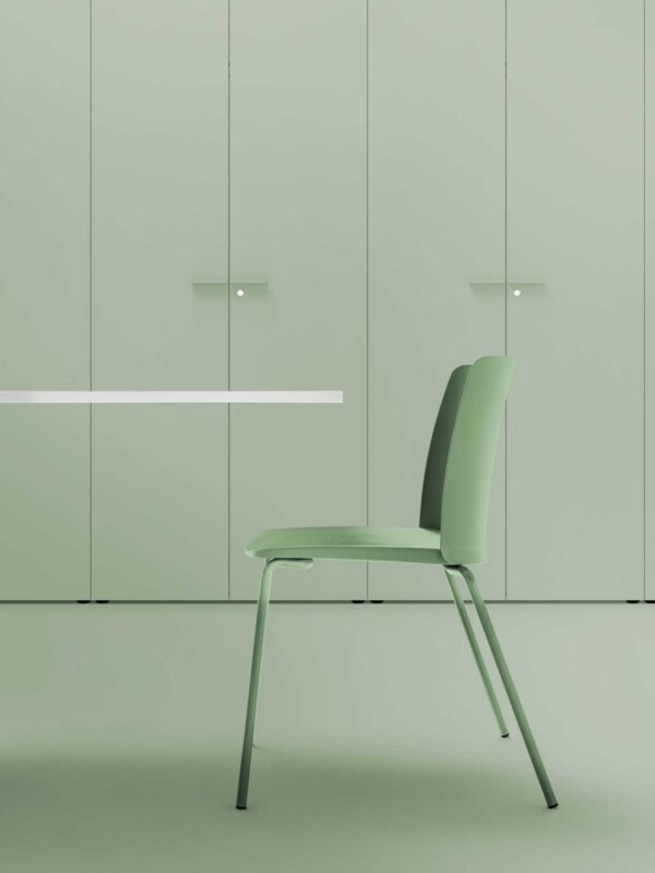 chaise empilable Daisy Bralco verte à pieds peints assortis, devant des armoires vertes en ambiance de bureau
