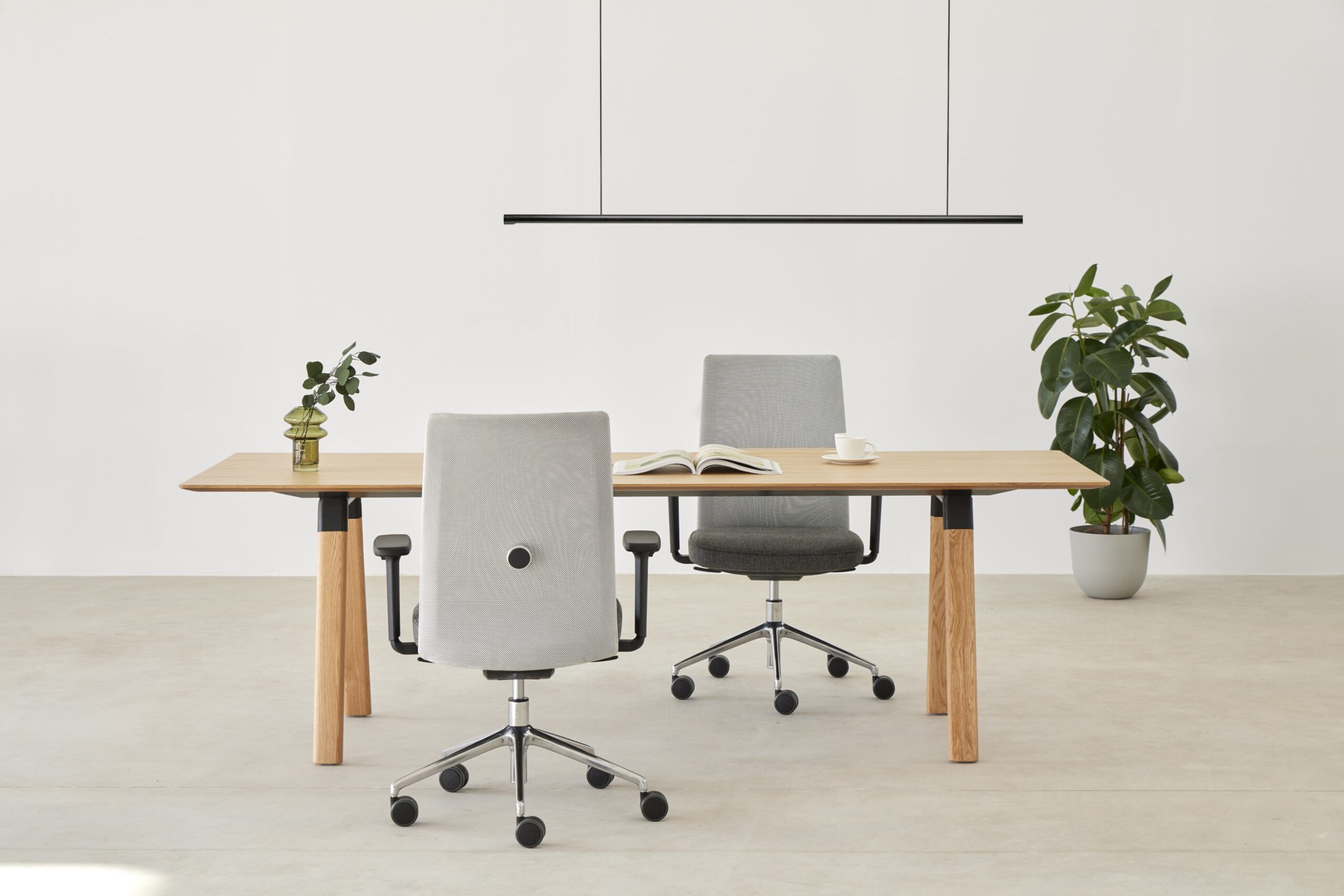 Chaise ergonomique Esitt par Inclass, dossier résille ou tapissé chaise ergonomique Inclass Esitt devant une table de travail sous une suspension linéaire