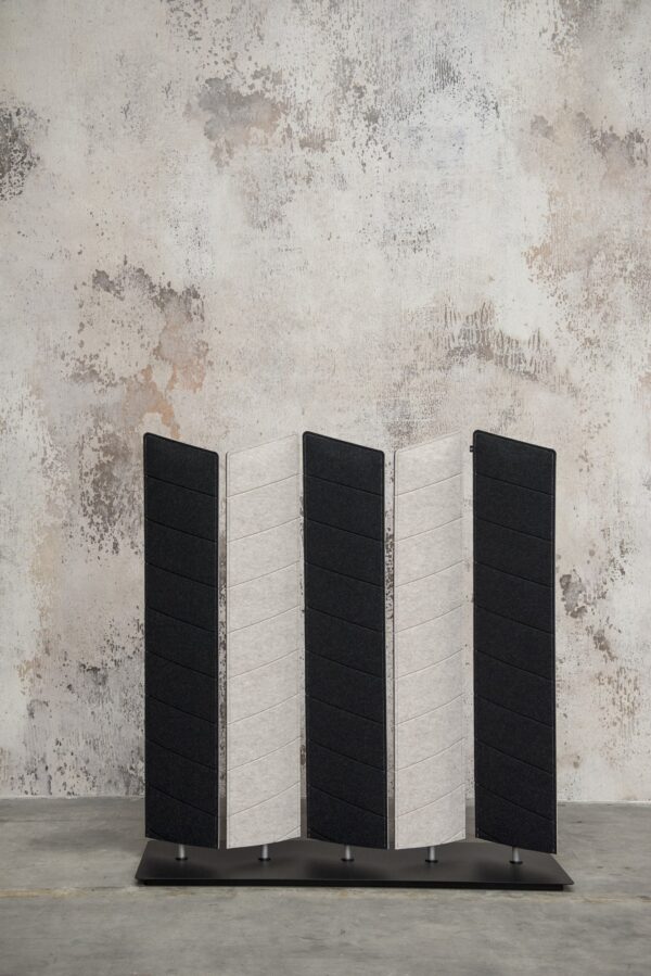 cloison acoustique BuzziBlinds à lames Wedge en feutre noir et gris clair devant un mur brut