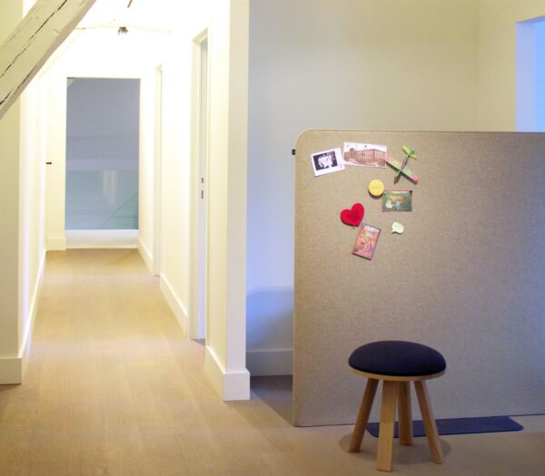 cloison acoustique BuzziFree BuzziSpace en feutre taupe dans un couloir de bureau avec des notes épinglées