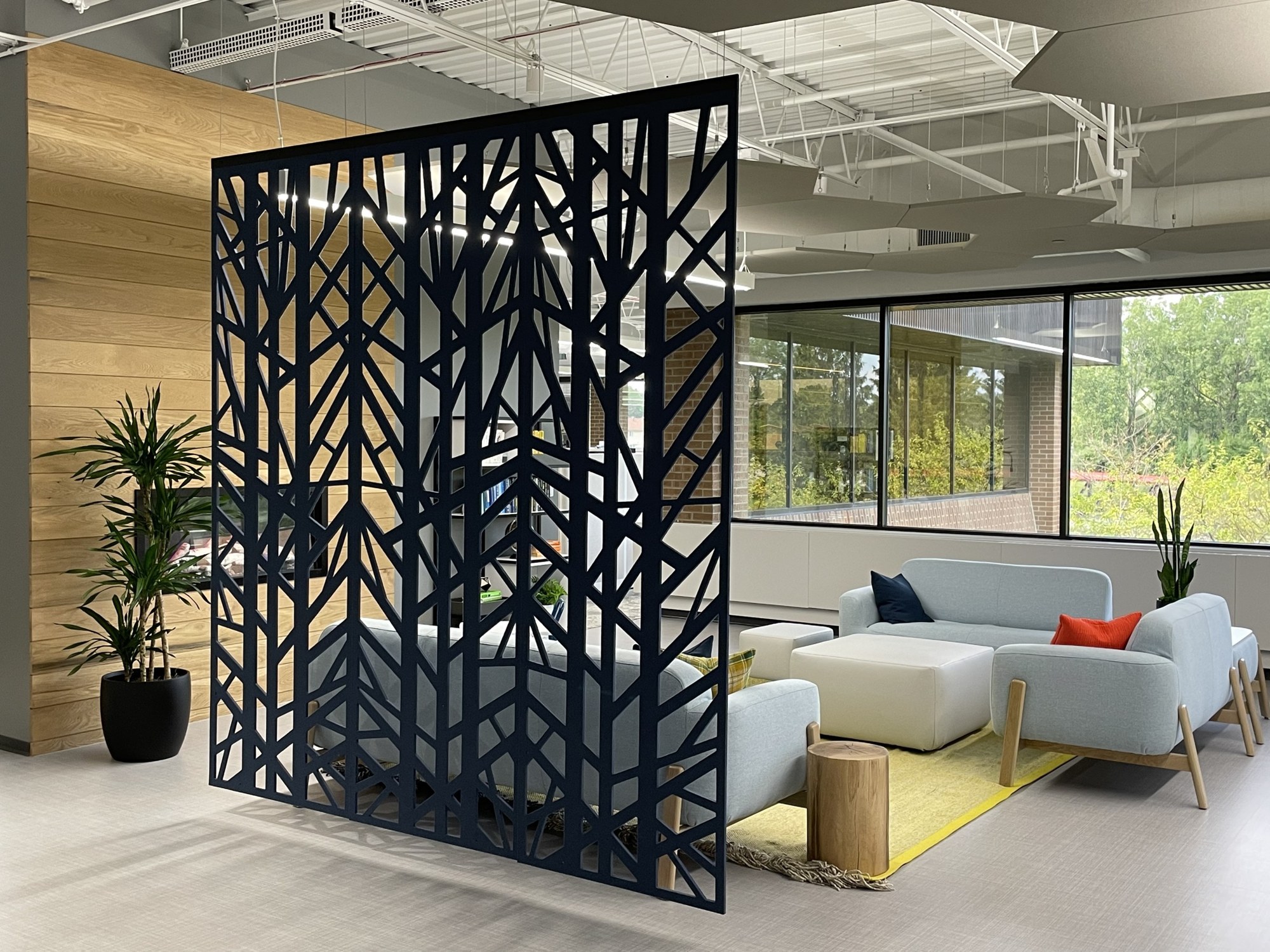 Cloison suspendue BuzziFalls par BuzziSpace, feutre à motifs découpés cloison suspendue BuzziFalls en feutre bleu marine au motif Birch devant un coin lounge
