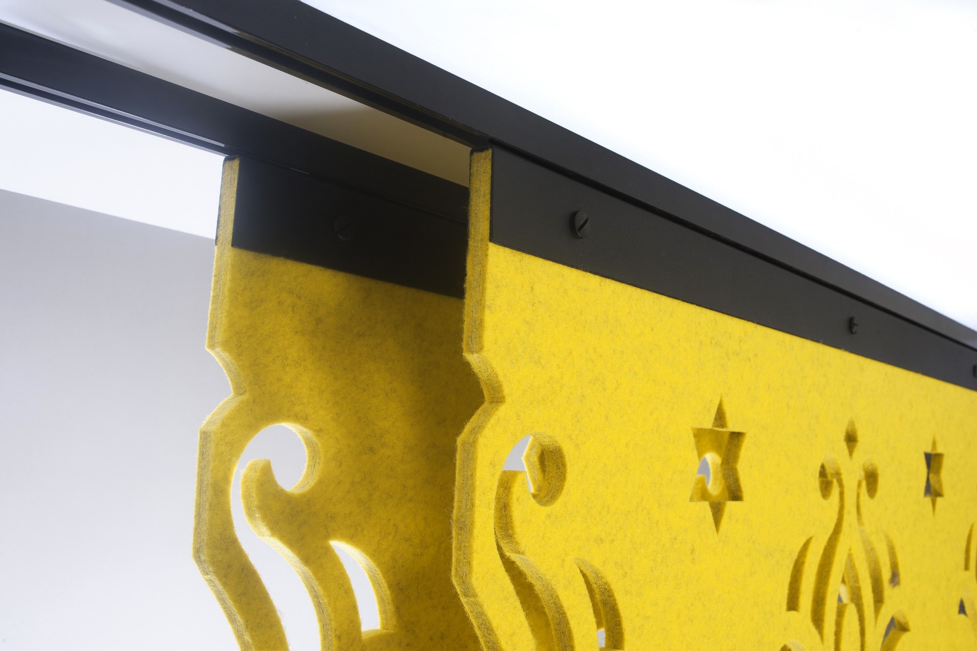 Cloison suspendue BuzziFalls par BuzziSpace, feutre à motifs découpés cloison suspendue BuzziFalls, détail du rail et de la fixation d un panneau de feutre jaune