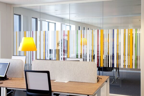 écran acoustique BuzziDesk en feutre gris clair sur un bureau en bois dans un open space