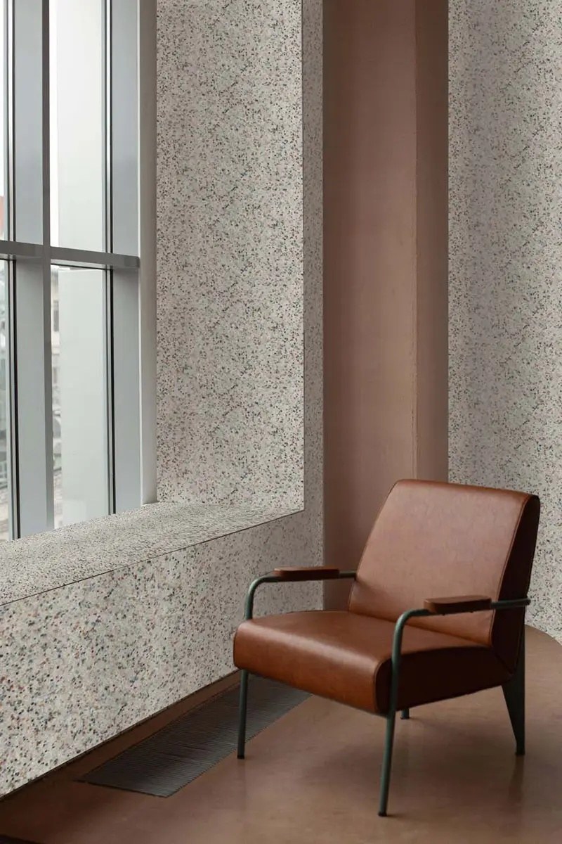 Feutre acoustique en rouleau ECO&PETfelt par Slalom, mur et formes feutre acoustique en rouleau Slalom ECO&PETfelt Terrazzo près d'un fauteuil en cuir