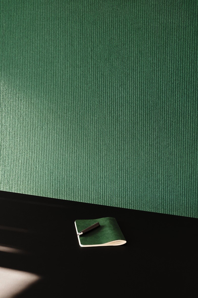 Feutre acoustique rayé PRESSEDfelt par Slalom, laine et PET feutre acoustique rayé Slalom PRESSEDfelt vert en lumiere rasante au dessus de bureau noir