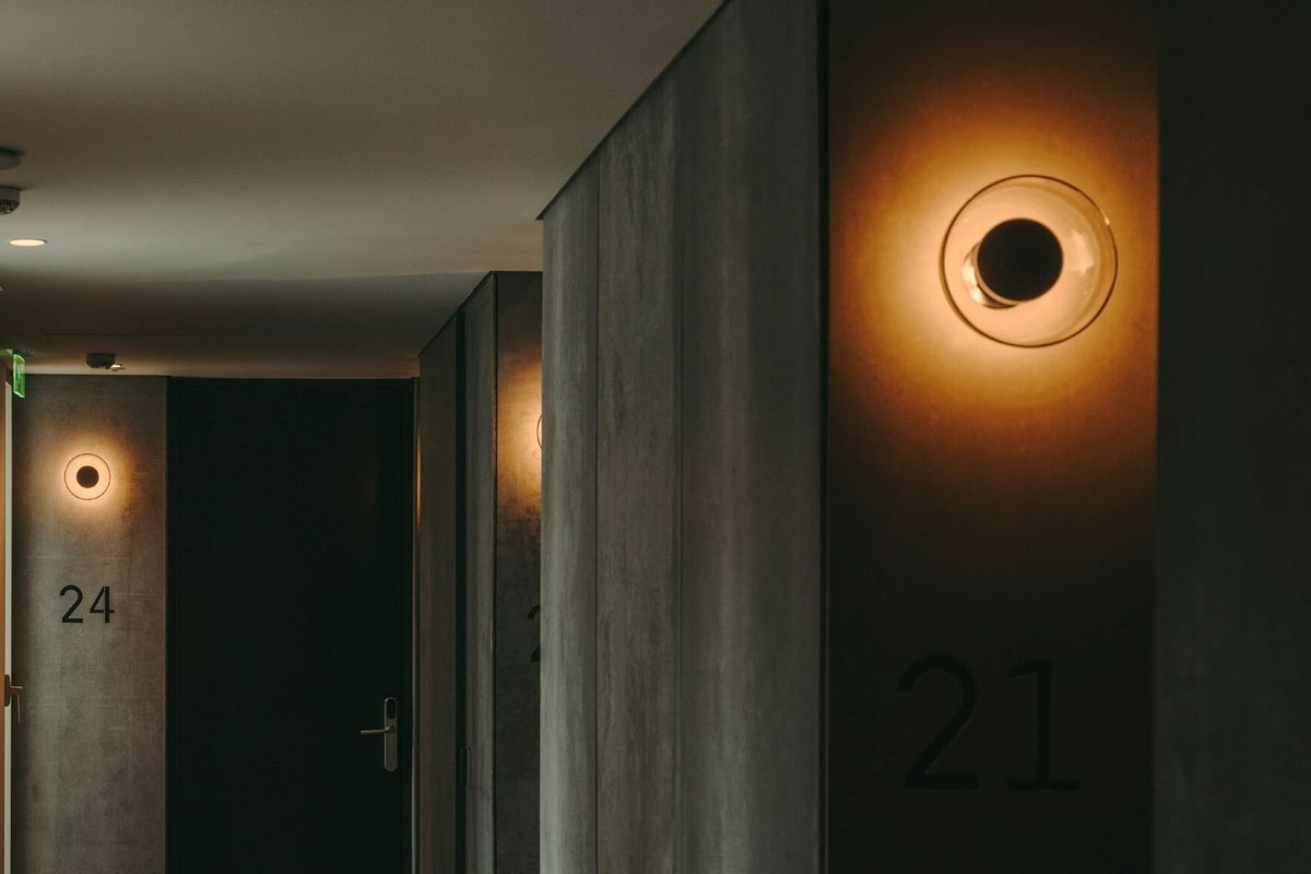 Fournisseur luminaires hôtel : comment bien choisir ? Fournisseur luminaires hôtel : appliques Marset Aura dans un couloir de chambres d'hôtel