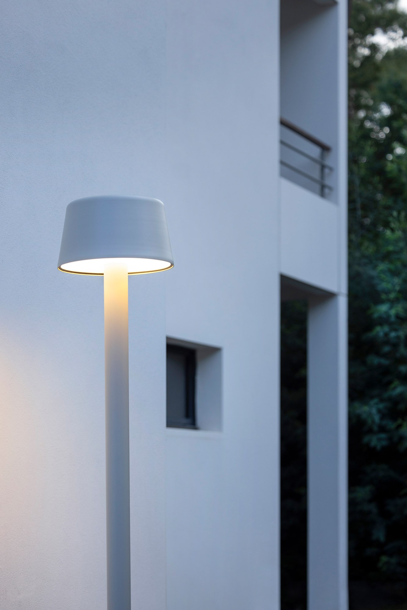 Lampadaire Bark par Roger Pradier, mât aluminium LED ou E27 lampadaire Bark gris soie, gros plan sur la tête conique devant une façade blanche