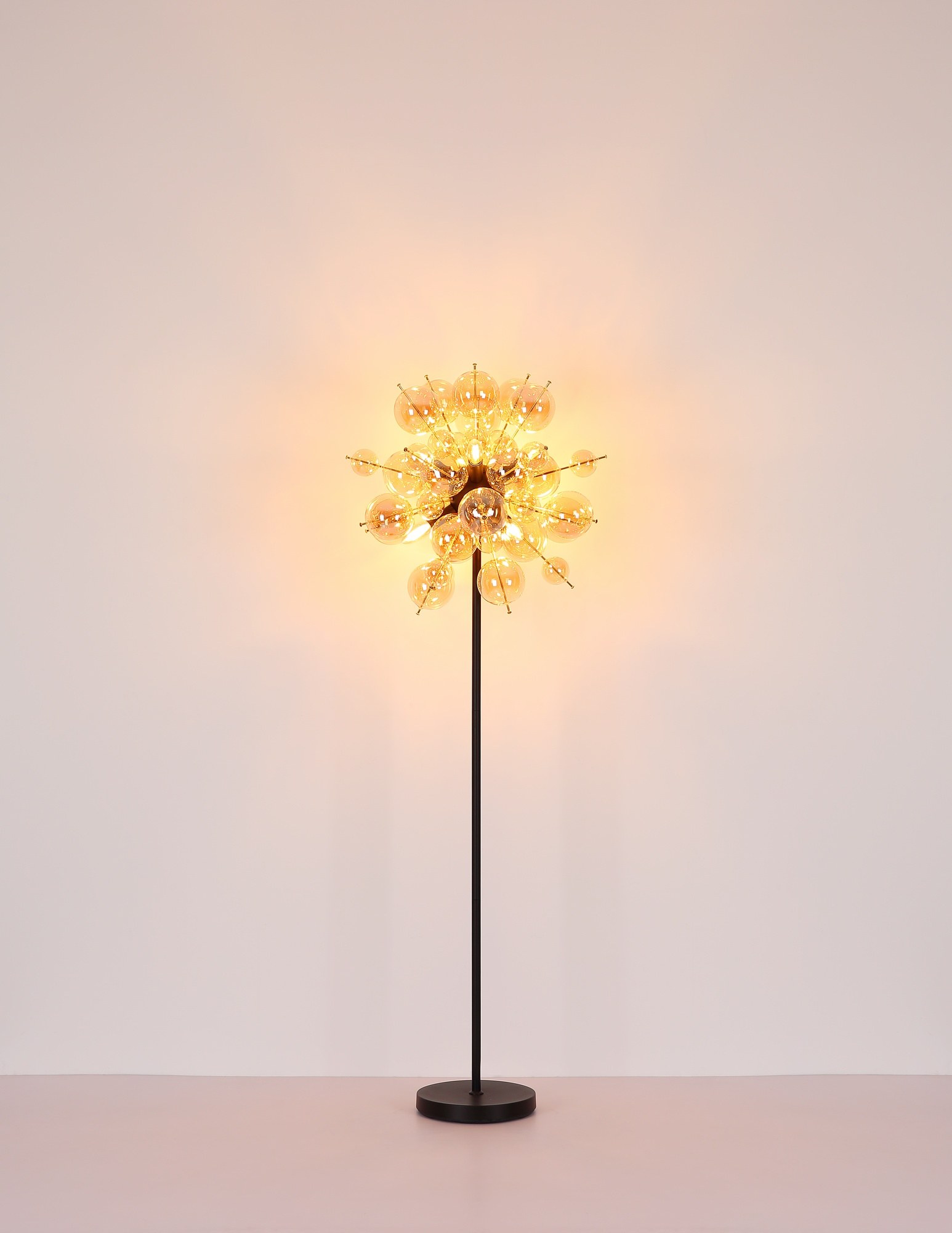 Lampadaire grappe de boules de verre ambre, fumé ou opale lampadaire grappe de boules de verre, version ambre allumée devant un mur clair