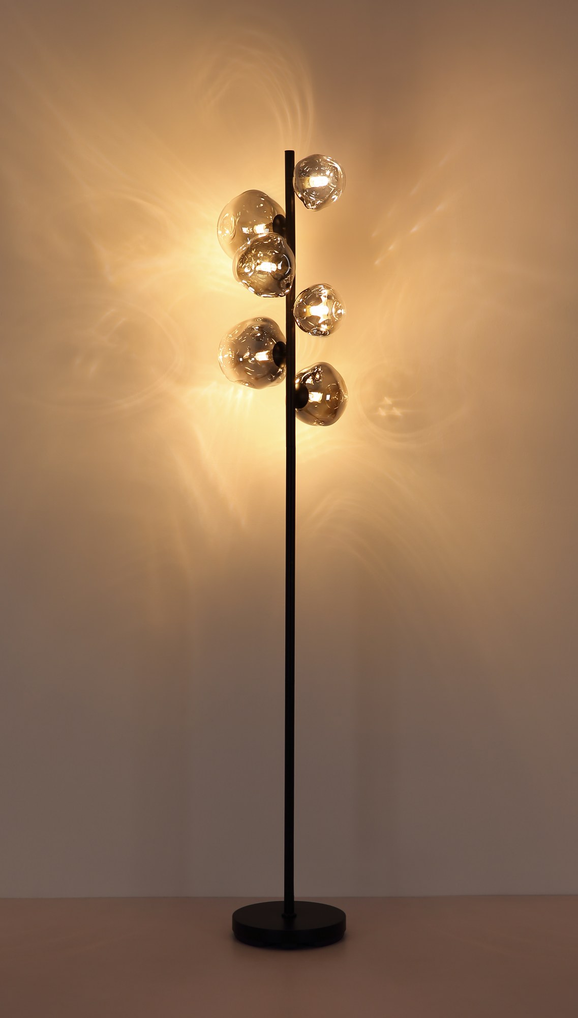 Lampadaire verre fumé noir, 6 lumières G9 et interrupteur lampadaire verre fumé 6 lumières allumé, reflets de lumière chaude sur le mur
