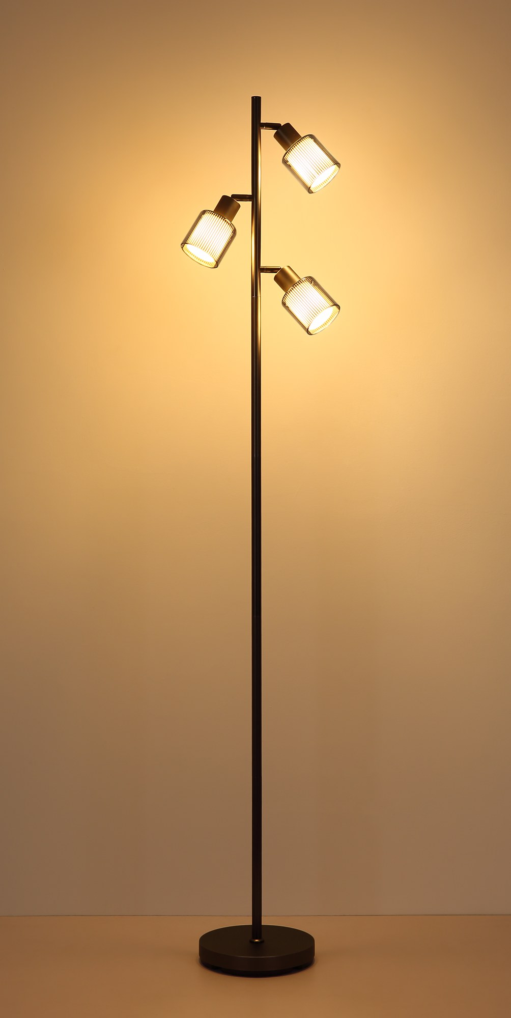 Lampadaire verre rayé gunmetal, 3 lumières E14 et interrupteur lampadaire verre rayé gunmetal allumé, lumière chaude sur le mur