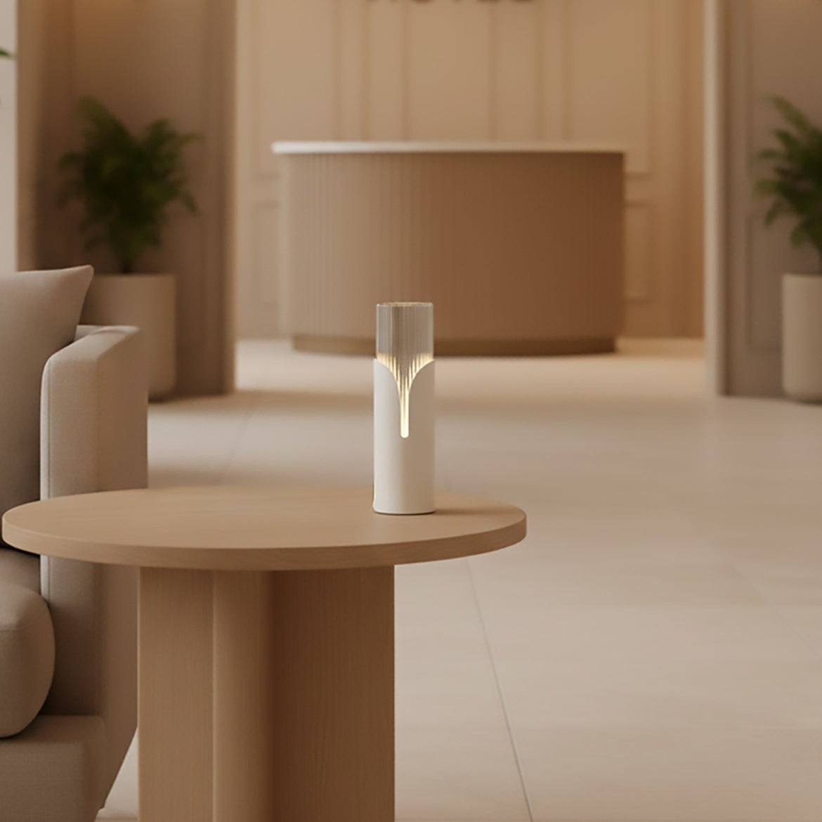 lampe à poser Bisel finition blanc mat allumée sur une table basse en bois dans un salon de réception