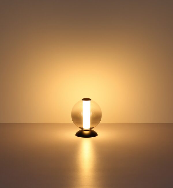 lampe à poser boule verre fumé allumée, lumière chaude sur une surface