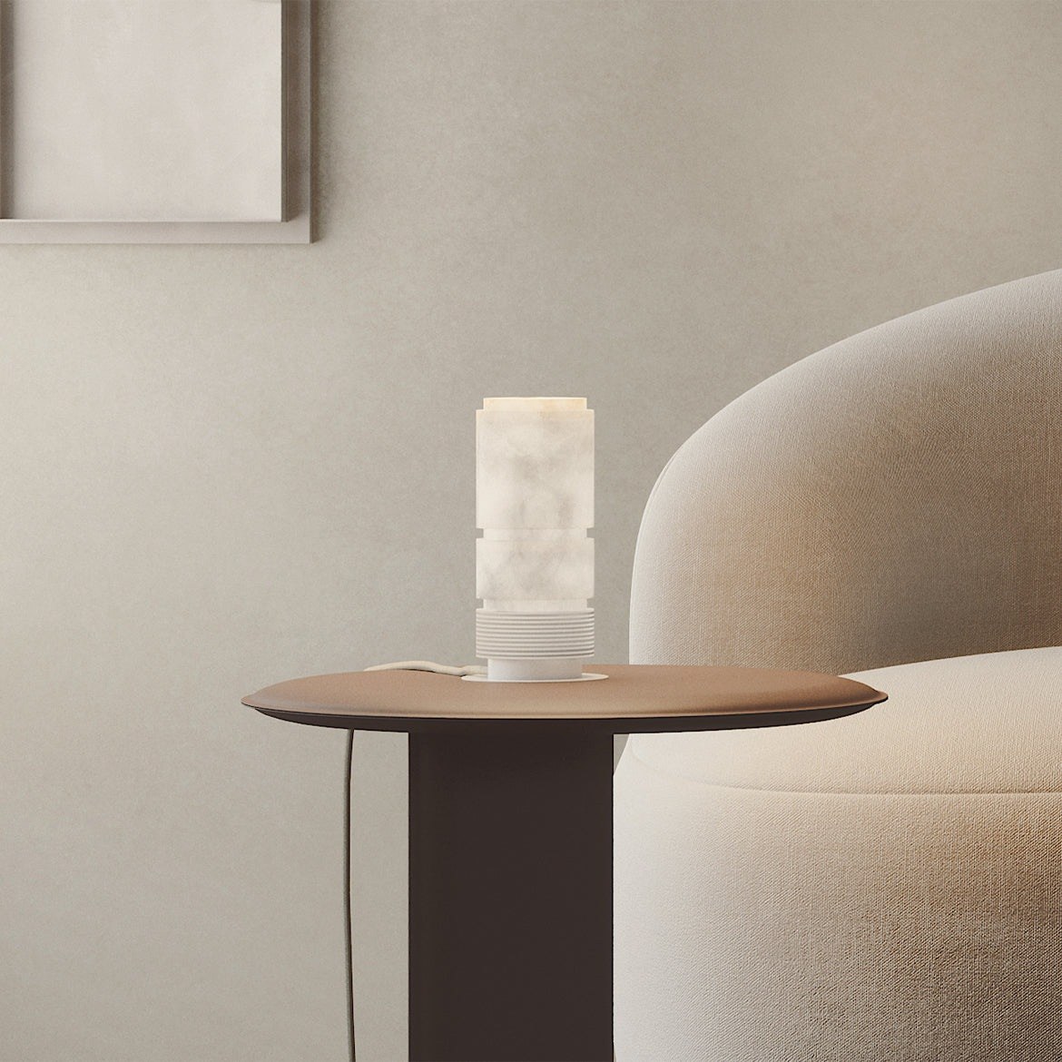 lampe à poser Bowie allumée sur une petite table ronde près du canapé arrondi beige