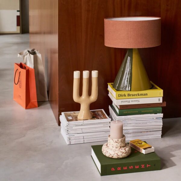 lampe à poser céramique Raikas Urban Nature Culture, en situation sur une pile de livres devant un panneau de bois