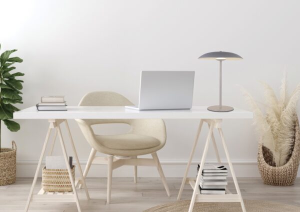 lampe à poser disque blanc sur un bureau clair à côté d un ordinateur