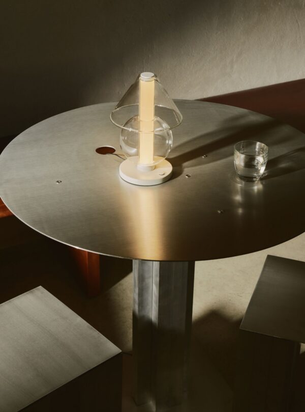 Lampe à poser Fragile S Marset allumée sur une table en métal