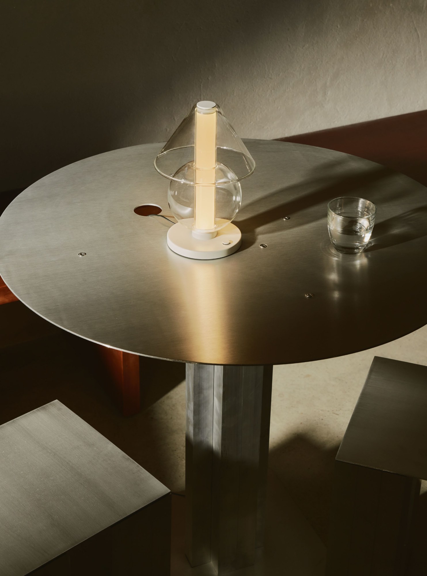 Lampe à poser Fragile S Marset allumée sur une table en métal