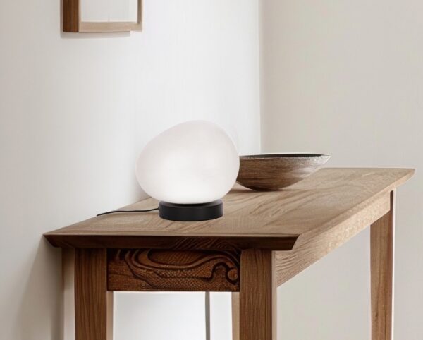 lampe à poser galet blanc posée sur une console en bois