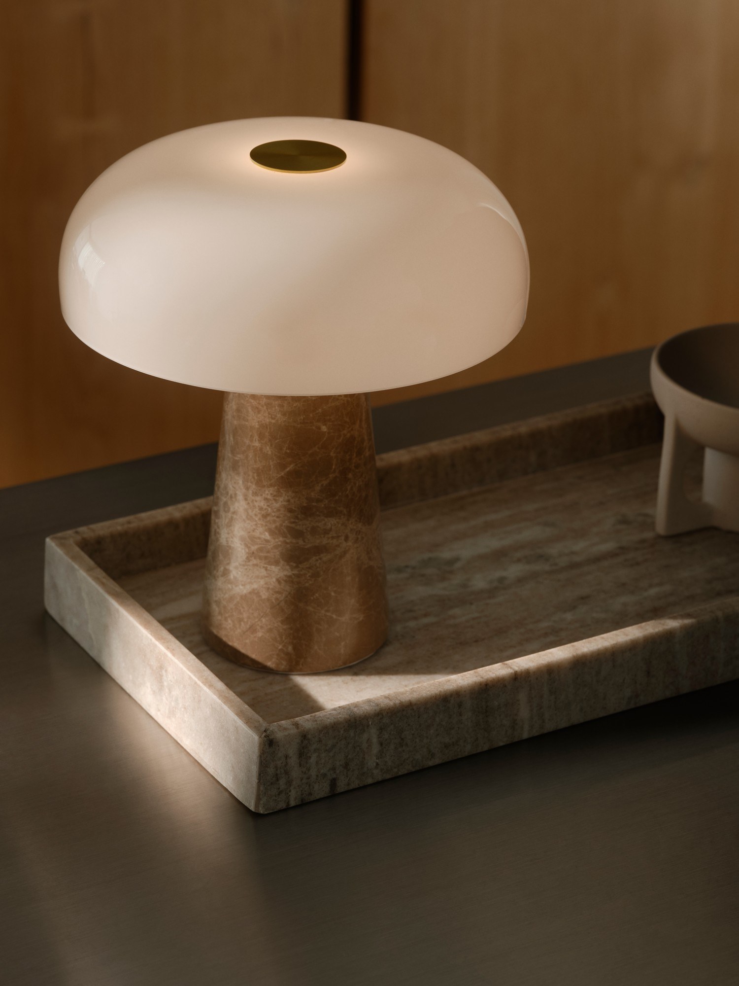 Lampe à poser Glossy Mini en pierre naturelle et verre opale par Design For The People lampe à poser Glossy Mini beige en marbre posée sur un plateau