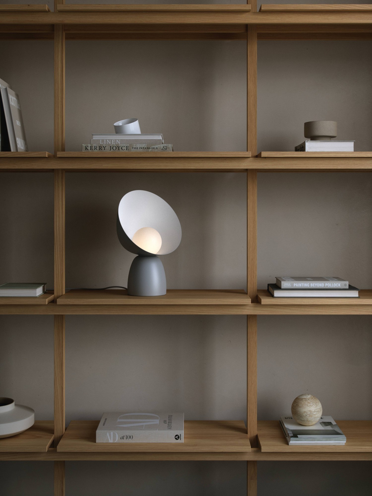 Lampe à poser Hello en métal et verre opale par Design For The People lampe à poser Hello grise posée dans une bibliothèque en bois