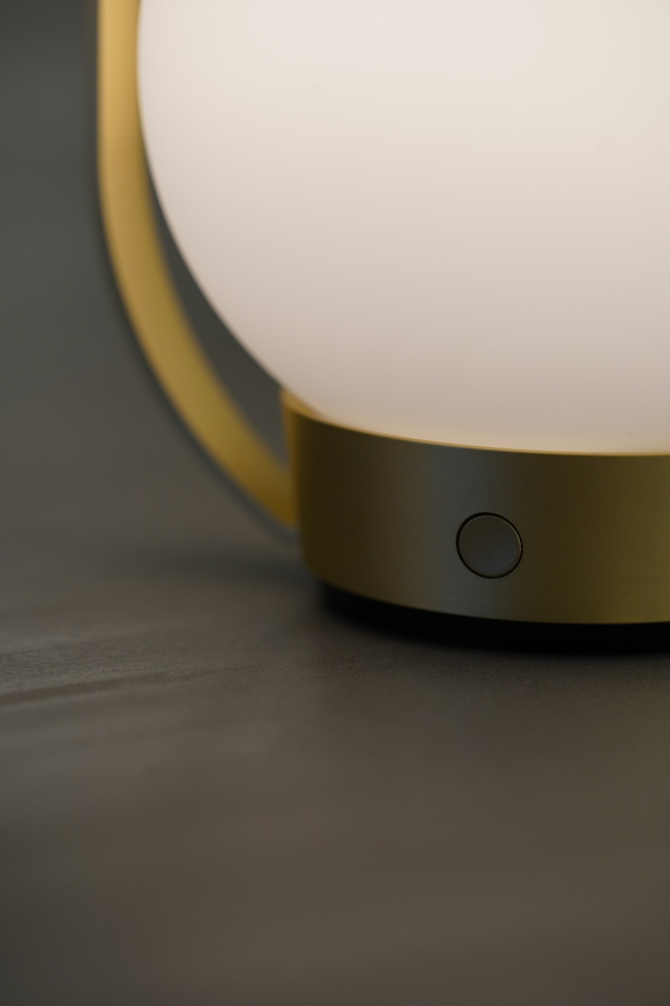 Lampe à poser Palla T1 sans fil en verre opale par Antidark lampe à poser Palla T1 Antidark, détail du bouton du socle et du cadre en laiton