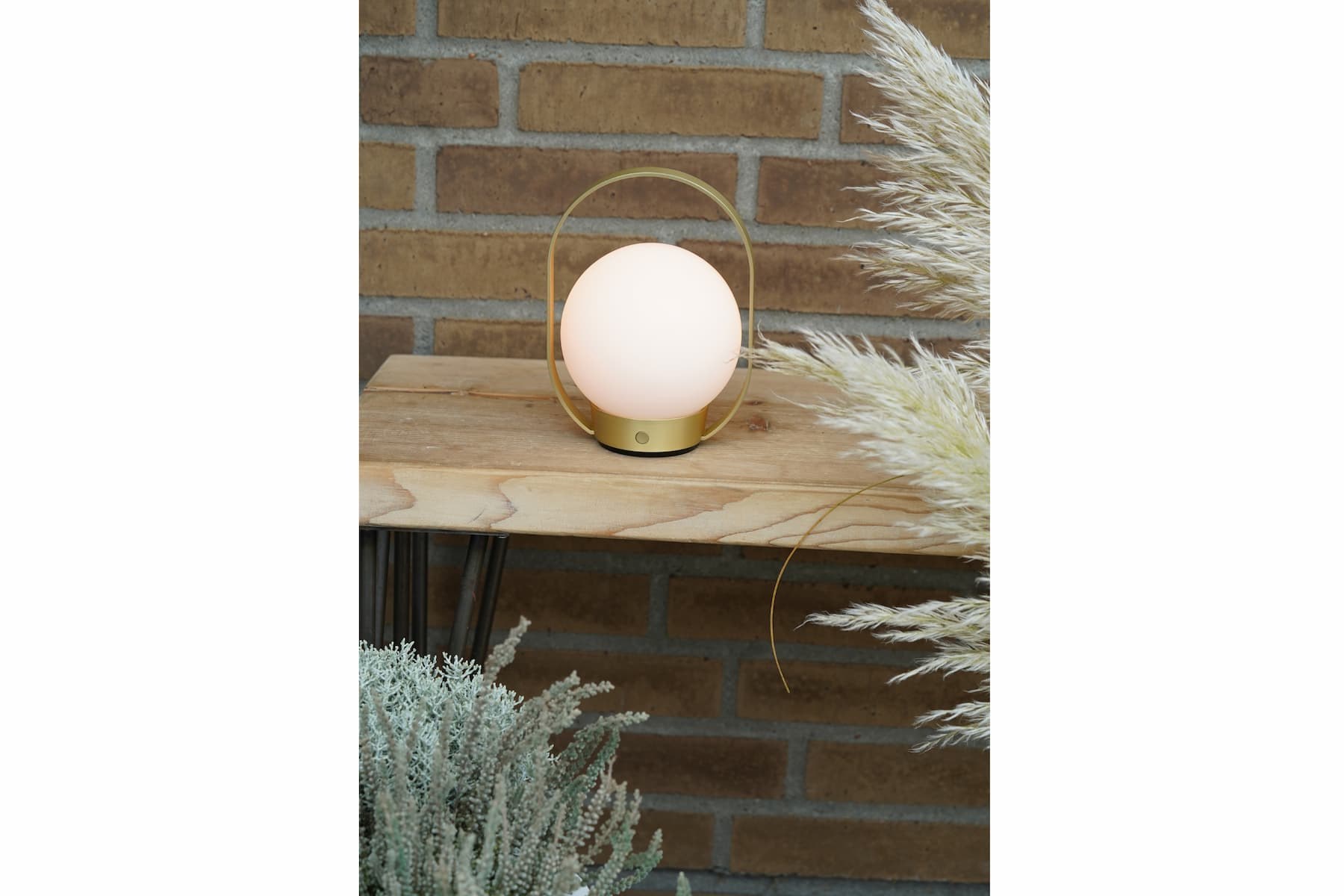 Lampe à poser Palla T1 sans fil en verre opale par Antidark lampe à poser Palla T1 Antidark en laiton IP54 sur une table extérieure