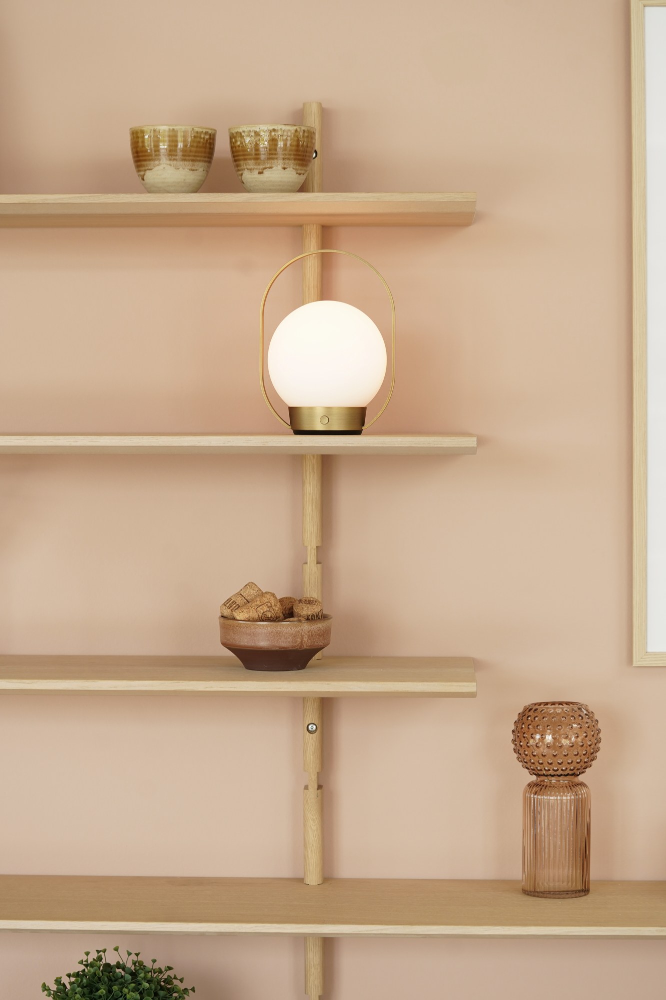lampe à poser Palla T1 Antidark posée sur une étagère dans un salon aux murs rose pâle