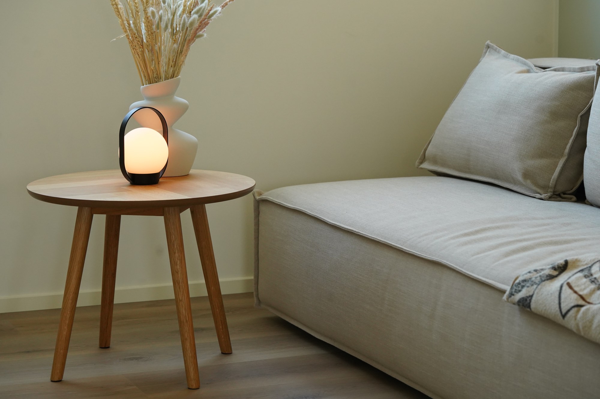 Lampe à poser Palla T1 sans fil en verre opale par Antidark lampe à poser Palla T1 Antidark noire sur une table d'appoint dans un salon