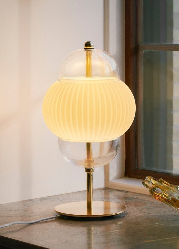 lampe à poser Shahin Design by Us, allumée sur un meuble près d'une fenêtre